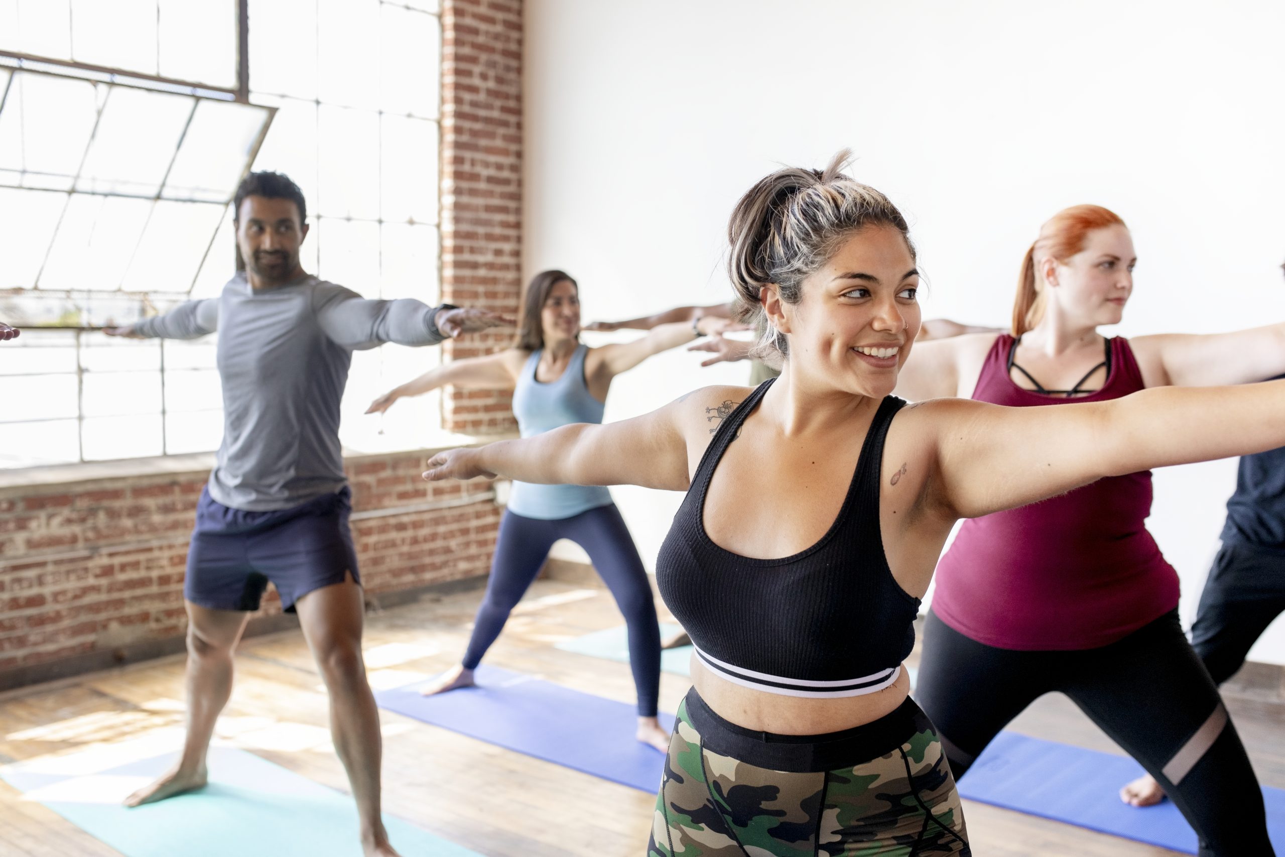 Diverse people practicing a Virabhadrasana yoga pose