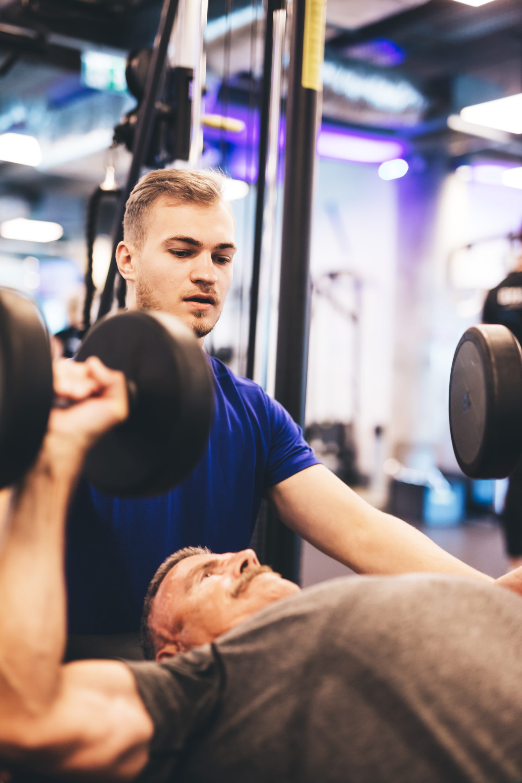 Personal trainer instructing older man during exercise.